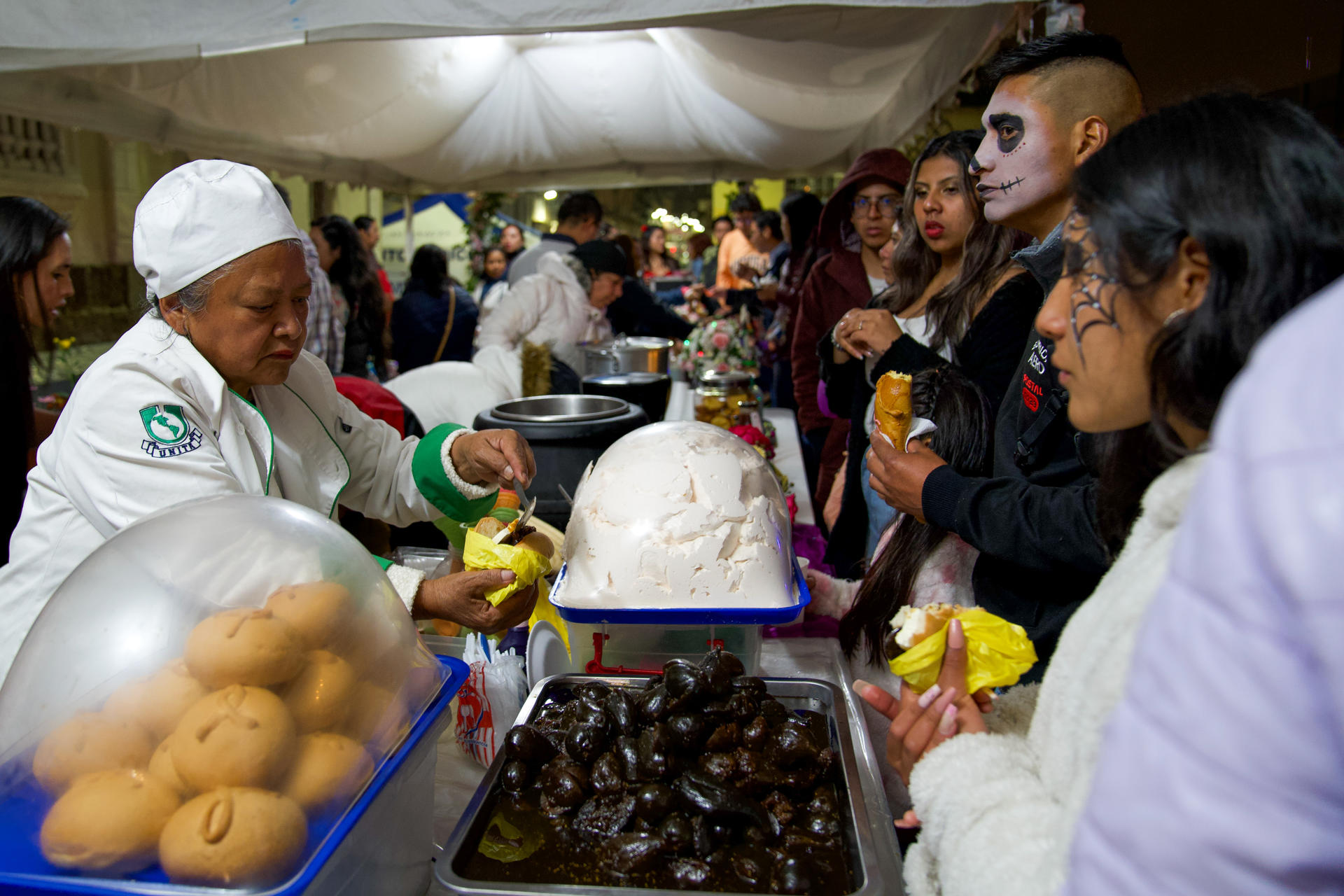 Personas disfrazadas consumen alimentos en Quito (Ecuador). EFE/Vicente Costales