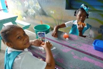 Fotografía de archivo en donde se ven dos niñas mientras toman su refrigerio en una escuela a las afueras de Castries, capital de la isla caribeña de Santa Lucía. EFE/Belén Delgado