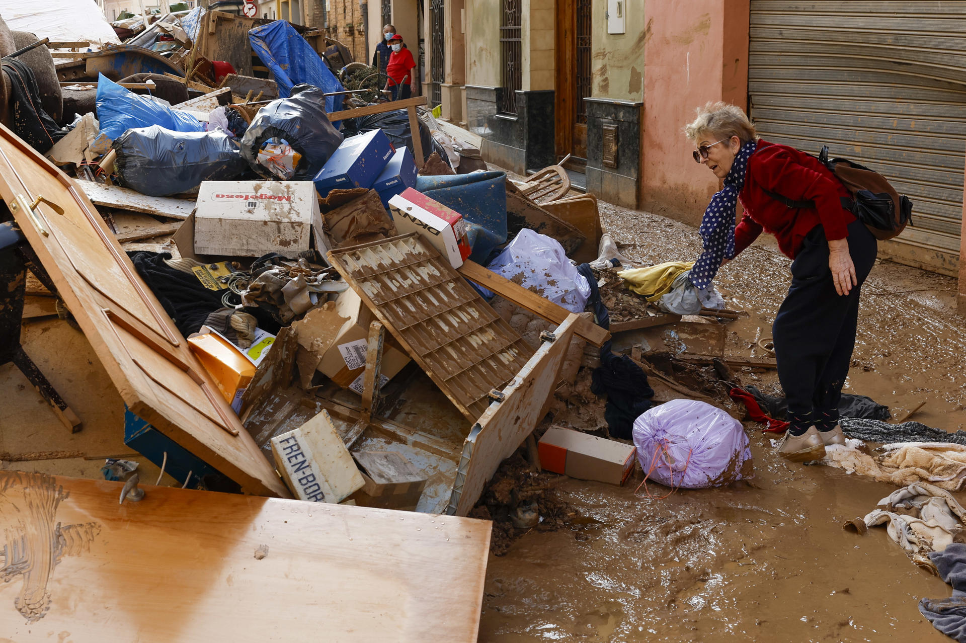 Una mujer junto a una montaña de escombros depositados en una calle de Catarroja, Valencia este martes, una de las localidades más afectados por las inundaciones. EFE/ Chema Moya