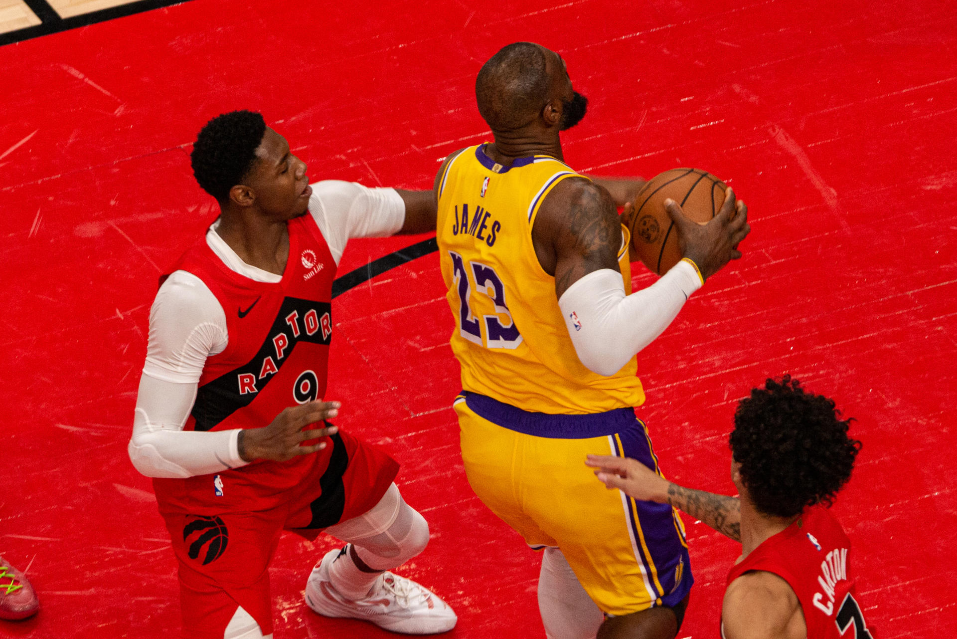 RJ Barrett (i) de los Toronto Raptors disputa el balón con LeBron James de los Ángeles Lakers, este viernes durante un partido de la NBA en el Scotiabank Arena, en Toronto (Canadá). EFE/ Julio César Rivas
