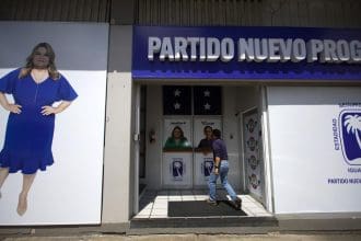 Fotografía del 25 de octubre de 2024 de un hombre entrando a la sede del Partido Nuevo Progresista (PNP), precedido por la foto de la candidata a gobernación, Jenniffer González, en San Juan (Puerto Rico). EFE/ Thais Llorca
