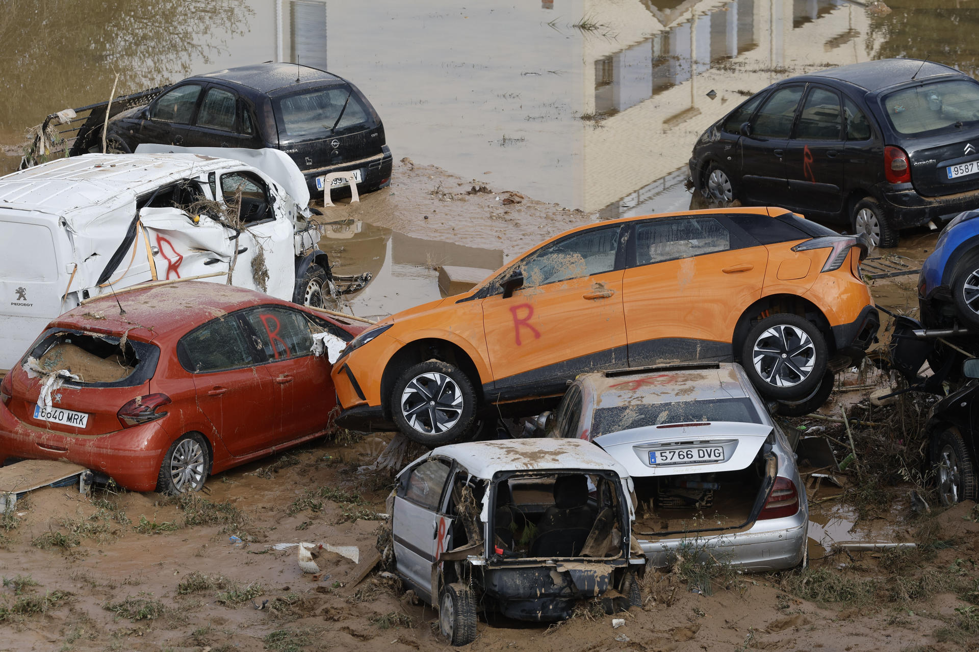Coches marcados con una "R" en la localidad de Alfafar, en Valencia, este sábado. Miles de personas se encuentran en la Ciudad de las Artes y las Ciencias de València esperando para subir a un autobús que les lleve a las zonas más afectadas por la Dana y ayuda en las labores de limpieza. Ataviados con palas, cepillos, baldes y litros de agua, llevan ya cerca de una hora conformando la fila para partir a pueblos como Sedaví, Alfafar o Catarroja. EFE/ Kai Försterling