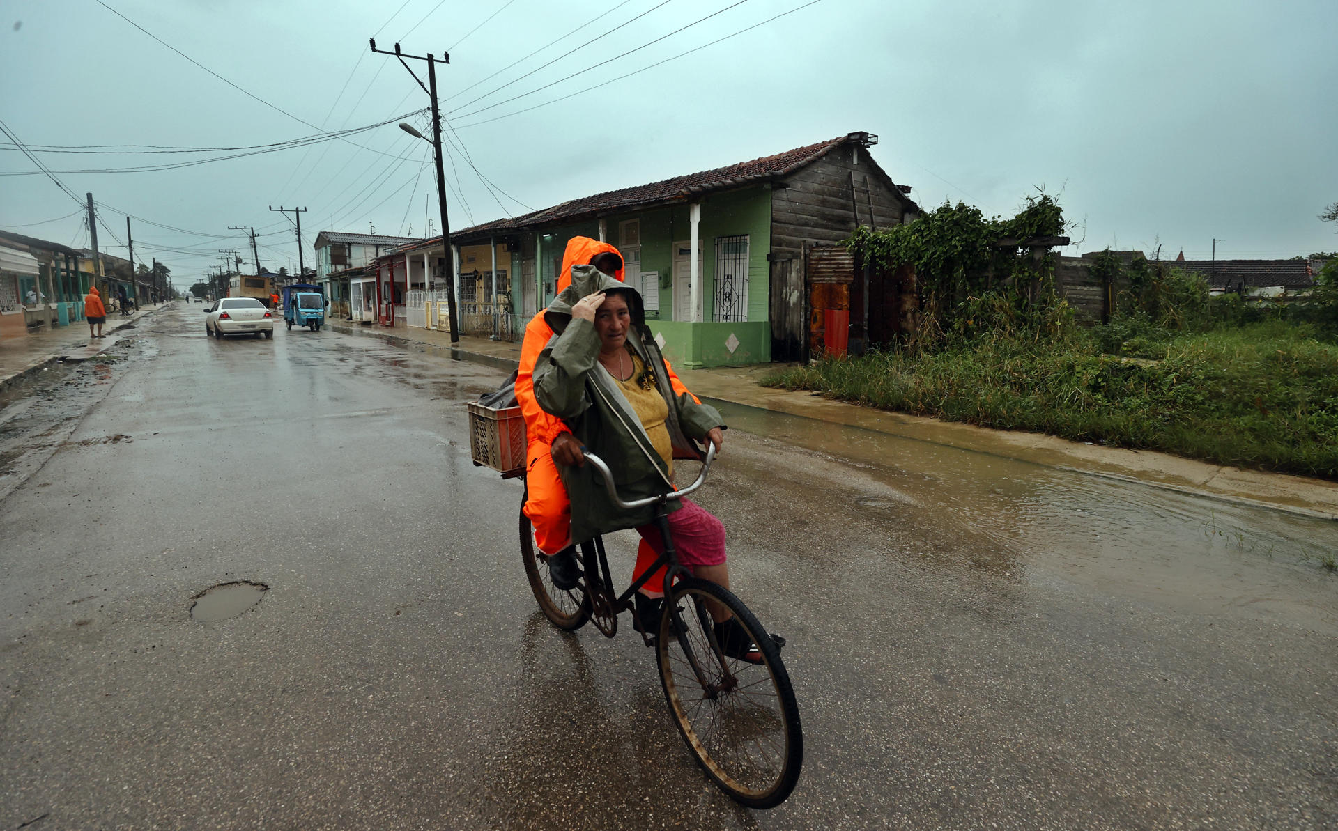 Dos personas se movilizan en bicicleta bajo la lluvia, este miércoles en Surgidero de Batabanó, un puerto pesquero en la provincia occidental de Mayabeque, a unos 50 kilómetros al sur de La Habana (Cuba). EFE/ Ernesto Mastrascusa