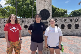 Ludmila Valle Betancourt (i), del Miami Democratic Socialists of America, Juan Osorio (c), director de registro de votos de Florida Rising Voices Collective (RVC) y María Victoria Chacón-Briceño (d), de Equality Florida, posan para EFE este viernes junto a la antorcha de la amistad en el centro de Miami, Florida (EE.UU.). EFE/Blanca Escriche